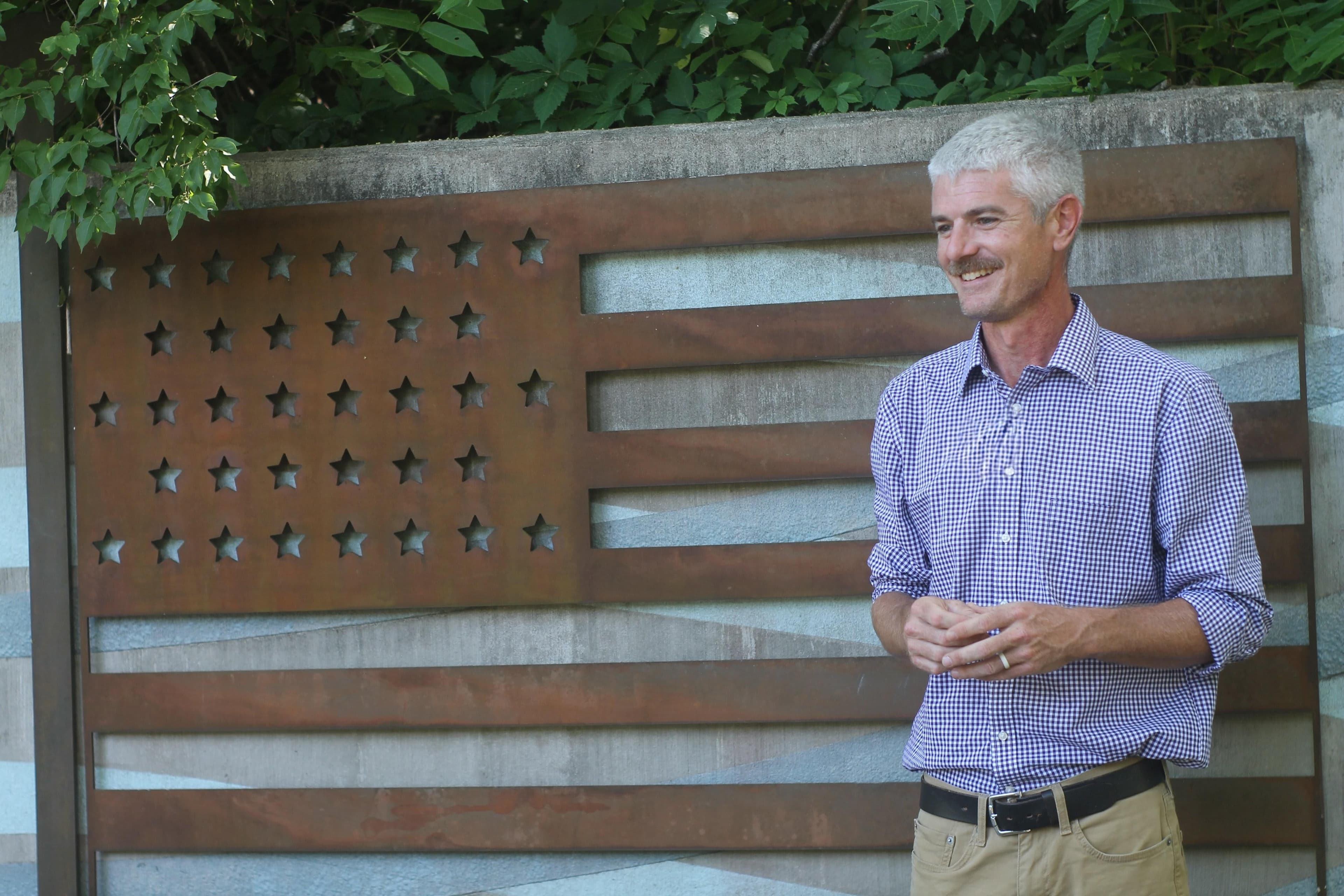 Tim Lanier in front of a steel American flag sculpture